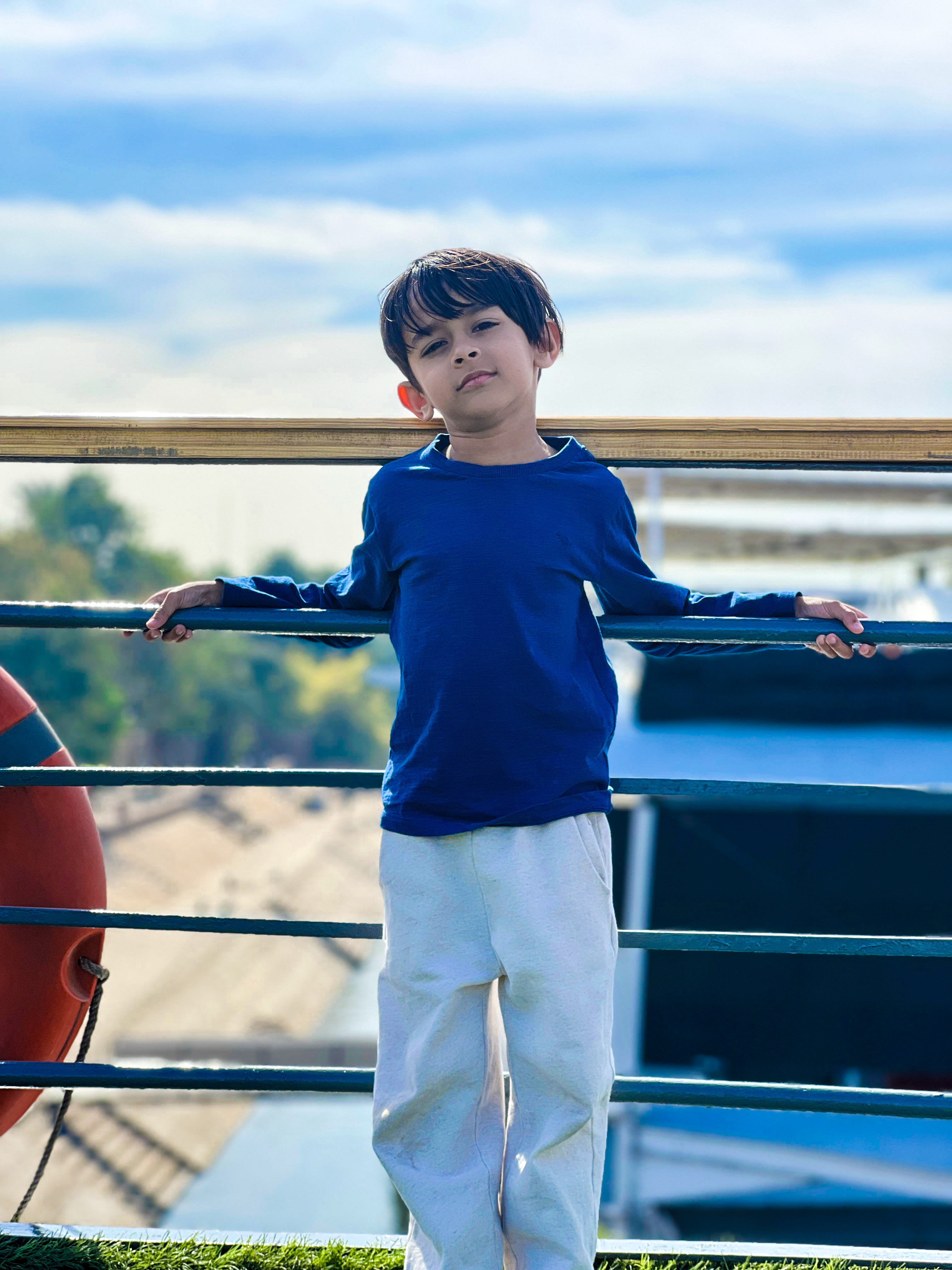 A young 6 year old boy standing between majestic ancient ruins wearing a yellow striped hoodie