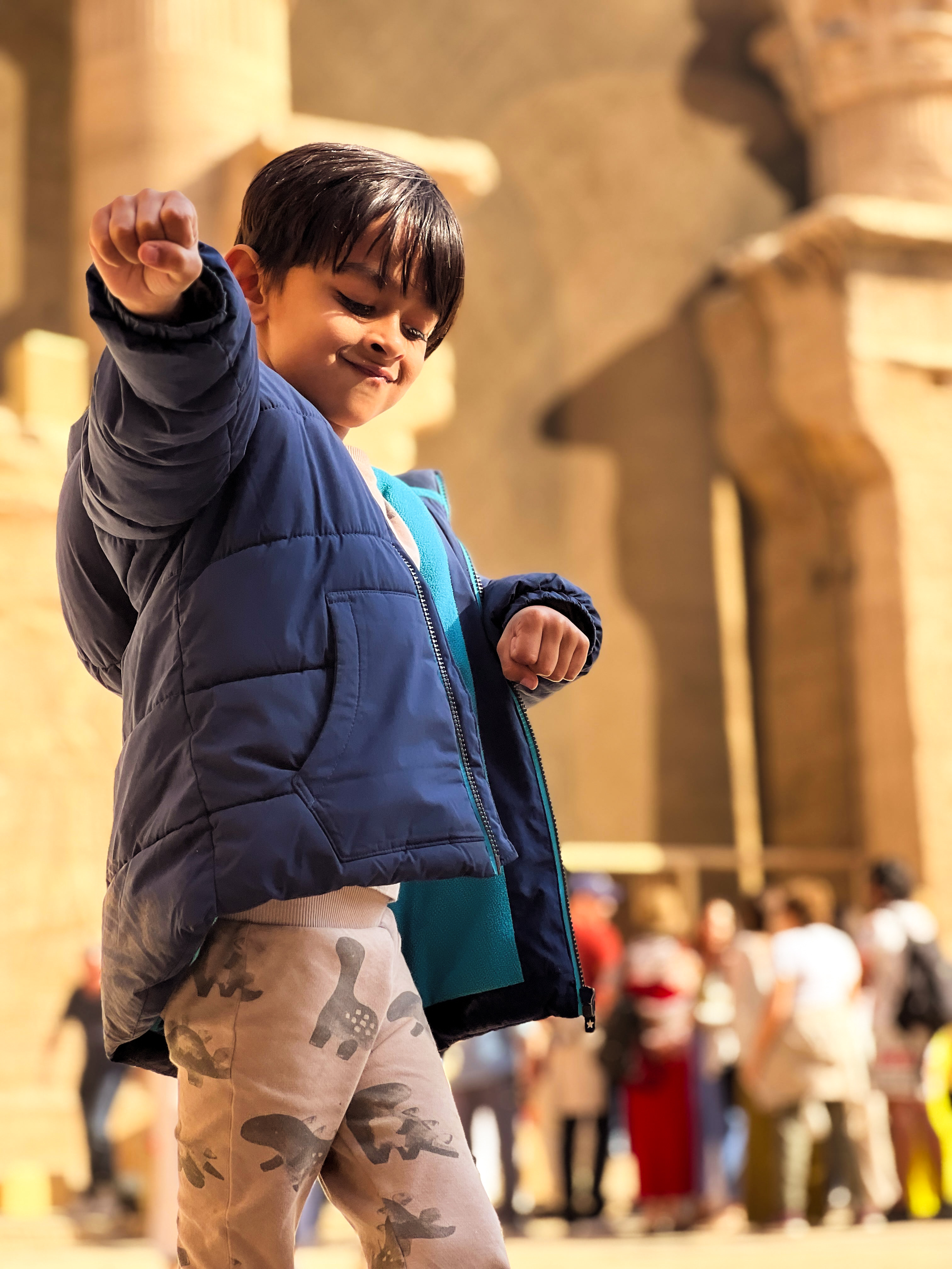 Young boy proudly holding an action camera in front of ancient temple walls
